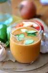 Cold Andalusian gazpacho in a glass with vegetables around it.