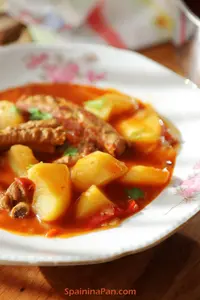 A Spanish potato and ribs stew on a plate.