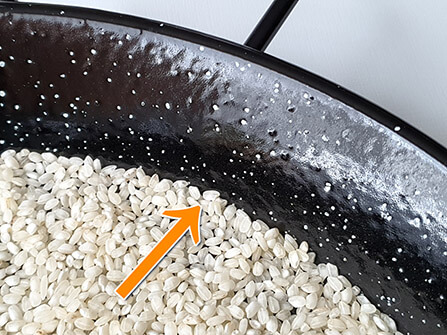 Rice touching the sides of a paella pan.