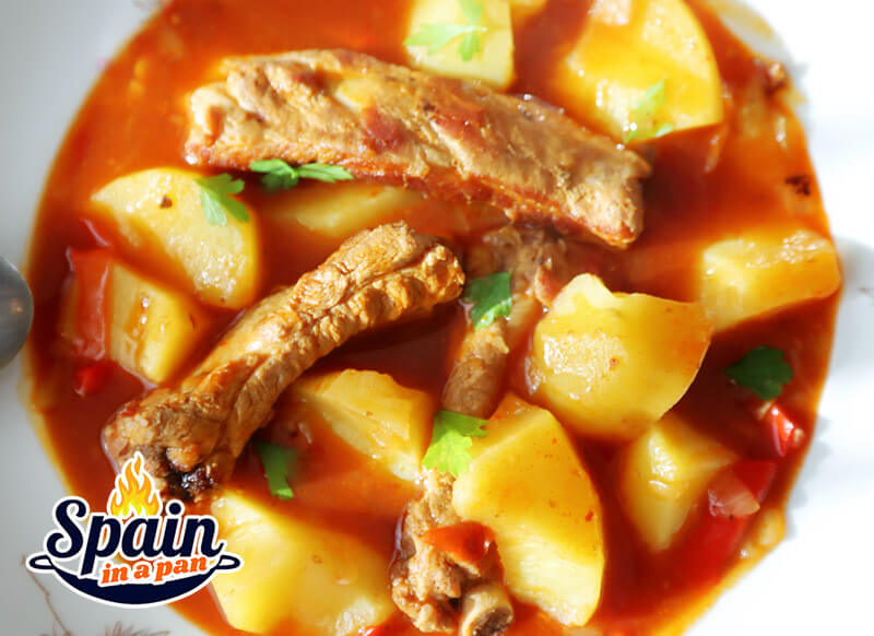 An appetizing Spanish potato and ribs stew on a plate.
