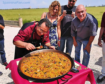 Spaniards gathered around one of the paellas for a traditional paella contest. Spaniards gathered around one of the paellas for a traditional paella contest.