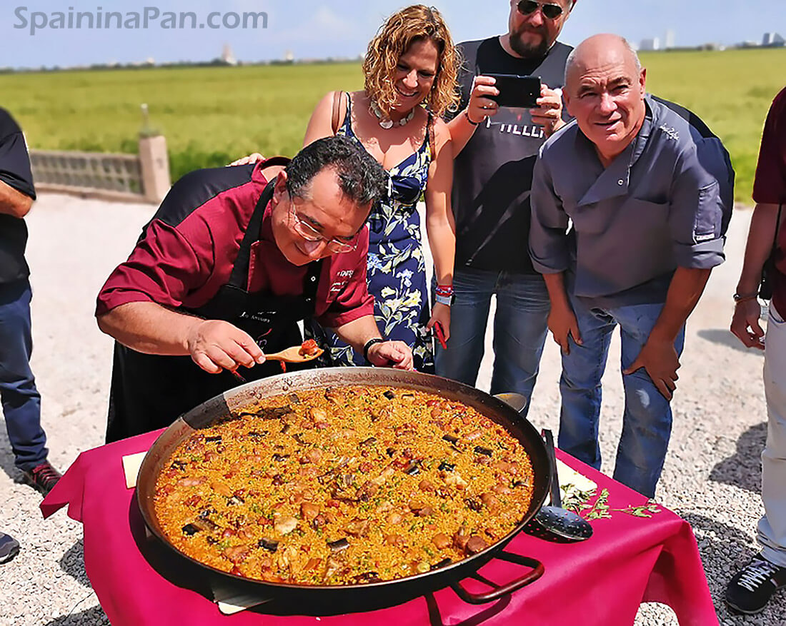 Spaniards gathered around one of the paellas for a traditional paella contest. Spaniards gathered around one of the paellas for a traditional paella contest.