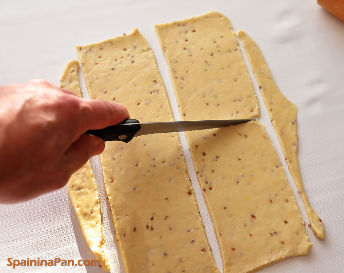 Cutting pestiños dough sheets on a white table.
