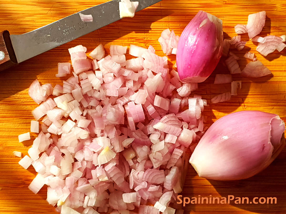 Finely diced shallots on a cutting board.