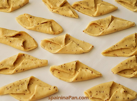 The pestiños dough rectangles folded on the table.