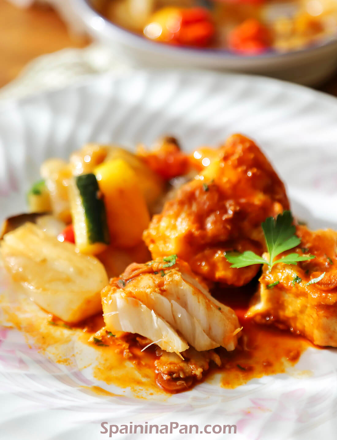 Spaish bacalao a la llauna served with grilled vegetables on a plate.