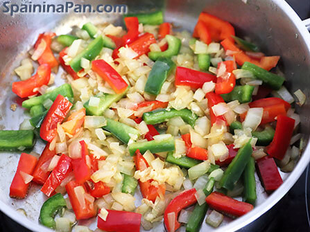 Preparing a sauté for the chicken and chorizo paella in a frying pan.