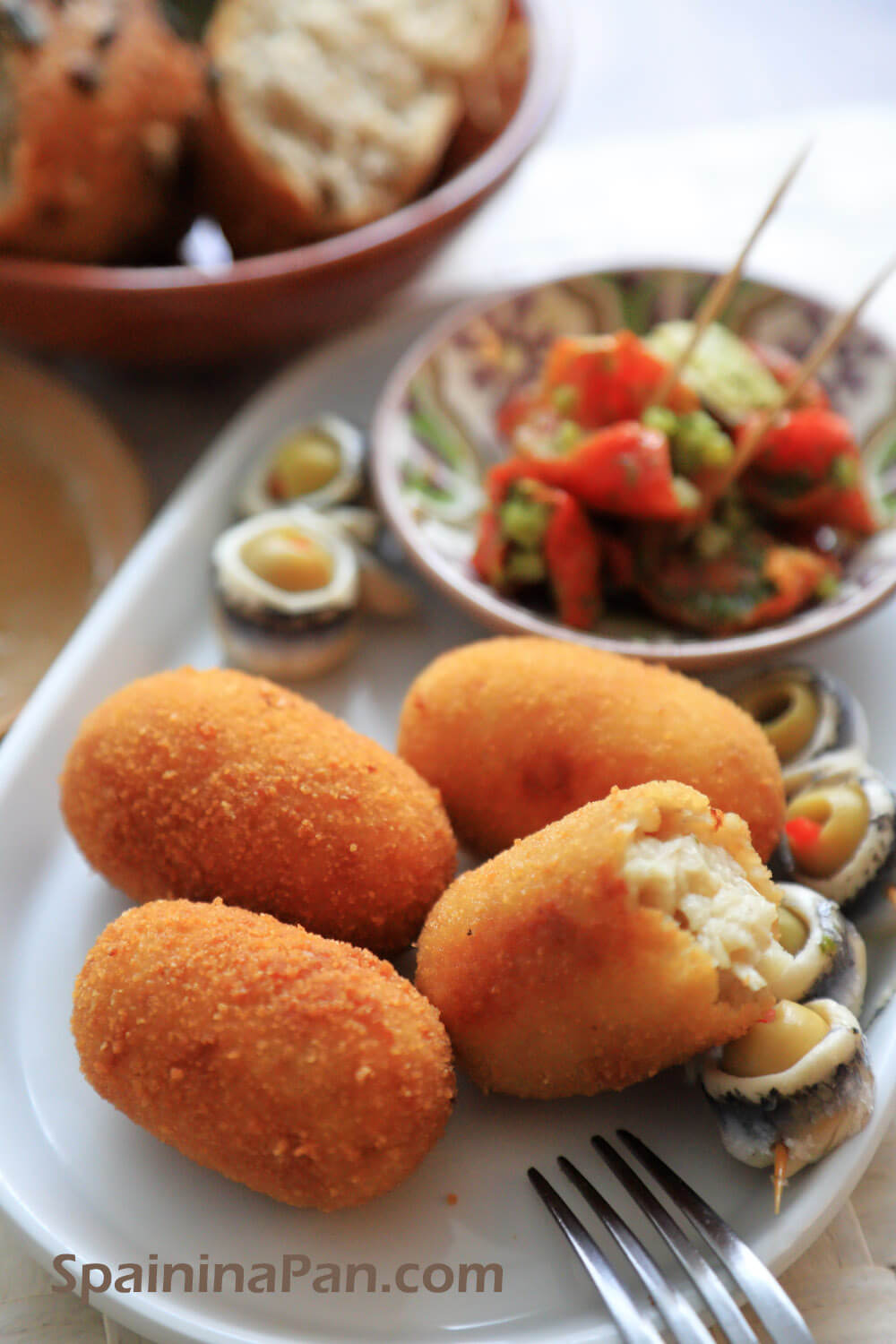 Spanish chicken croquettes on a plate with dried tomatoes.