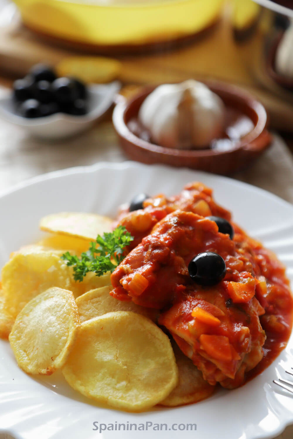 Spanish chicken with tomato sauce and chips on a plate.