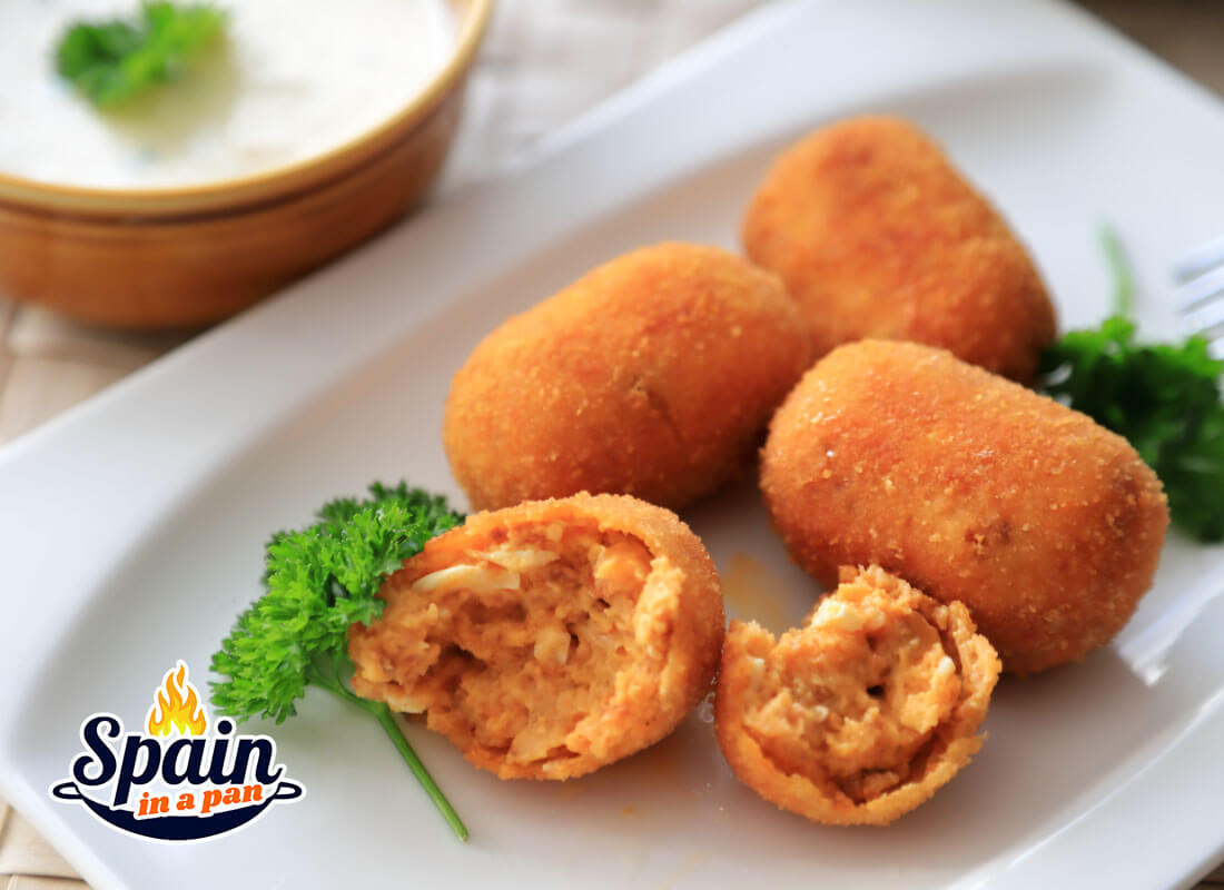 Spanish chistorra and eggs croquettes with dip on a plate.