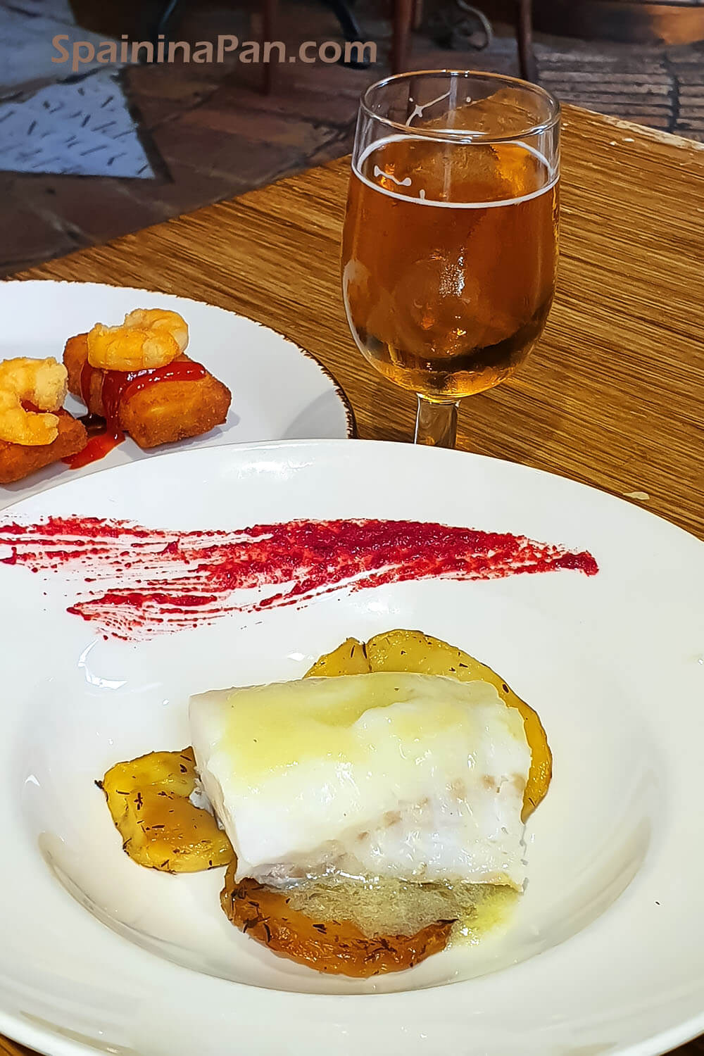 Spanish bacalao al pil pil sauce on a plate with bear and croquettes