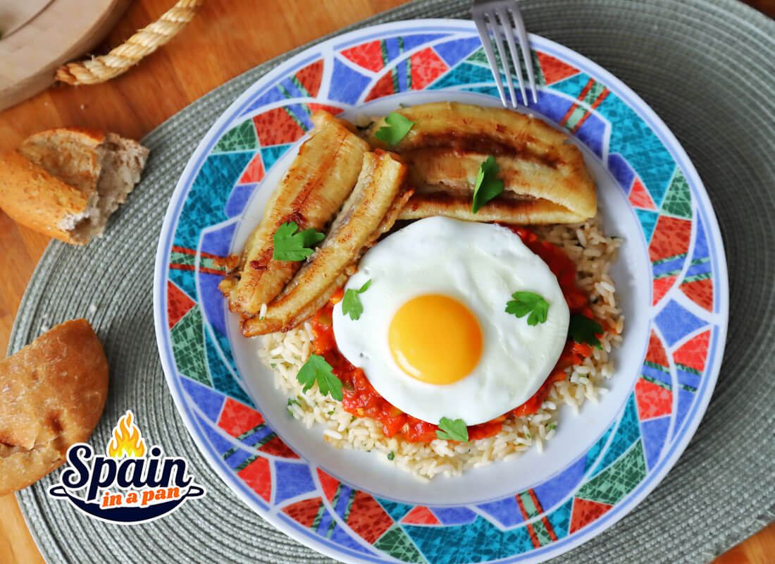 Spanish Cuban rice with egg and bananas on a decorative plate with bread.
