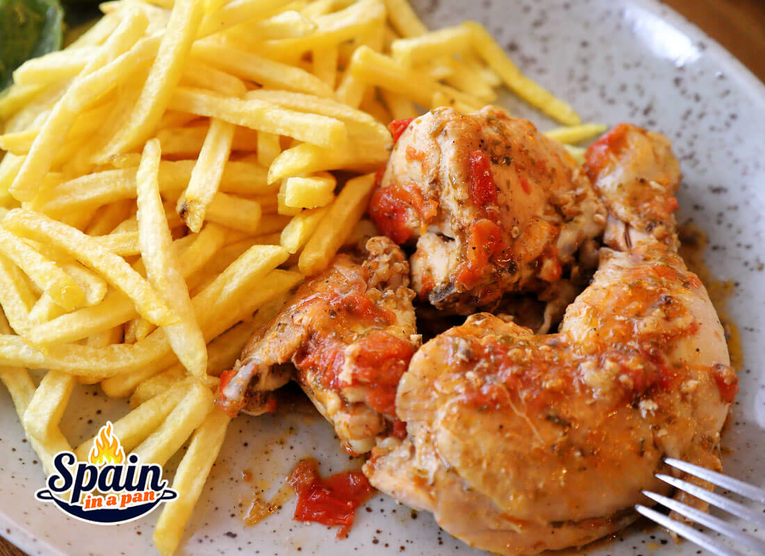 Spanish garlic chicken with fries served on a plate.