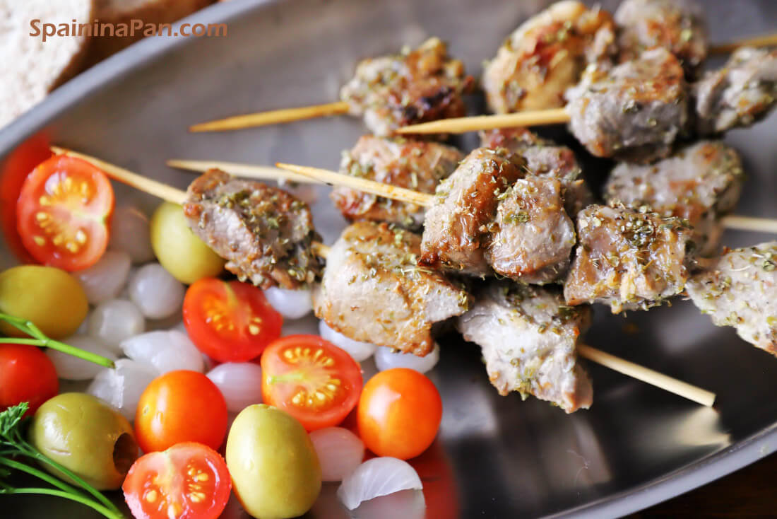Spanish garlic pork skewer pinchos with salad on a dish.