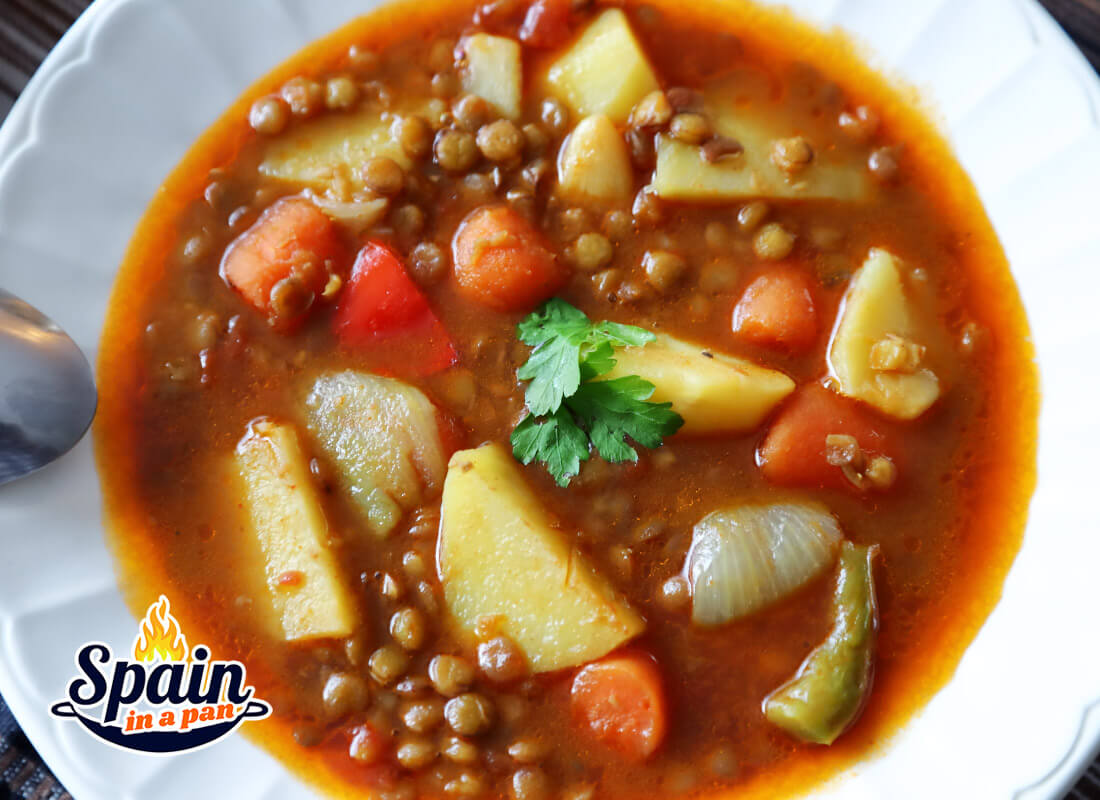 Delicious Spanish lentils with potatoes soup in a deep plate.