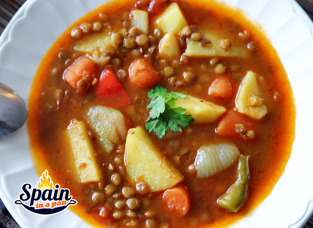 Delicious Spanish lentil soup with potatoes and carrots in a deep plate.