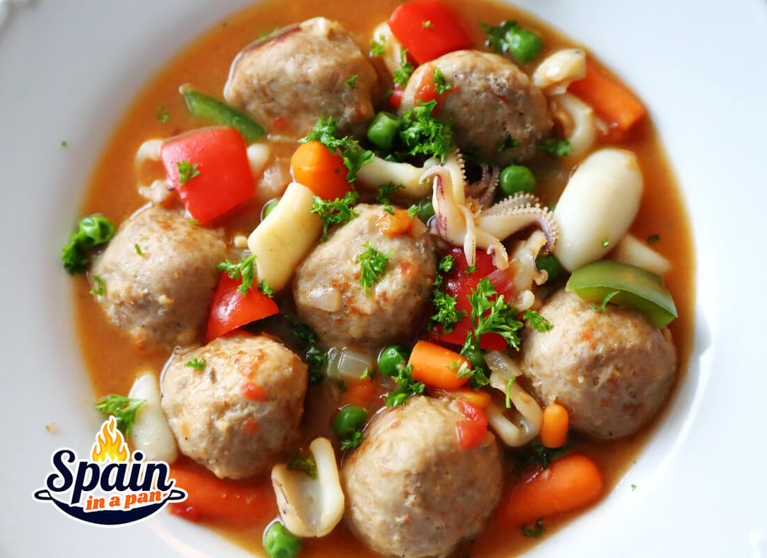 Spanish meatballs with sepia cuttlefish stew in a white plate.