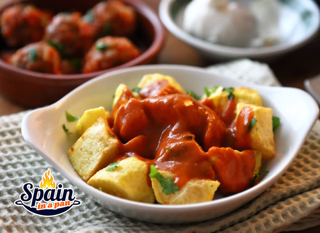 Patatas bravas without tomato in a white tray.