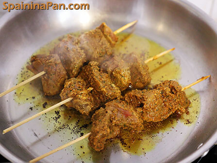 Pinchos morunos frying in a regular steel pan.