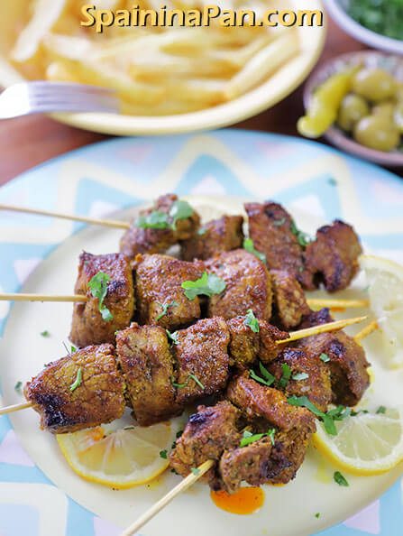 Spanish pinchos morunos on a decorative plate.