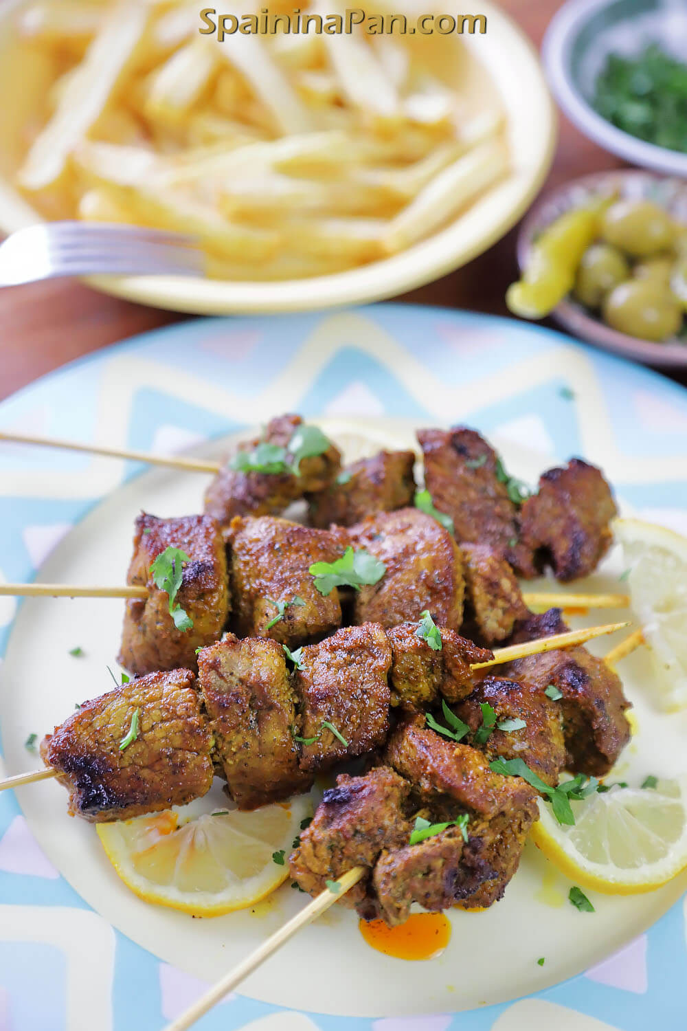 Spanish pinchos morunos on a decorative plate.