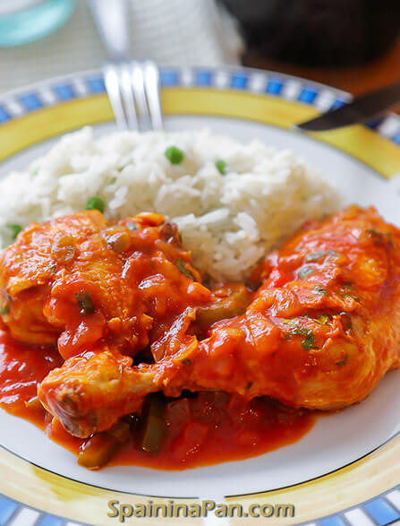 Spanish pollo al chilindron chicken with white rice o a plate.