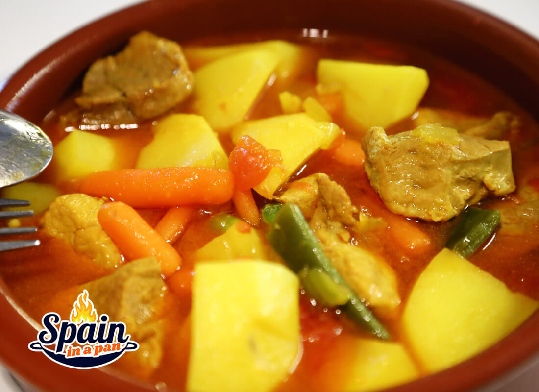 A Spanish pork and potato stew in a earth tray.