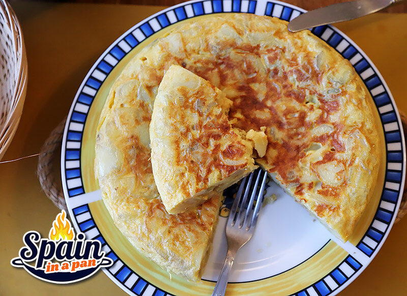 Tortilla española with a cut slice on a decorative plate.