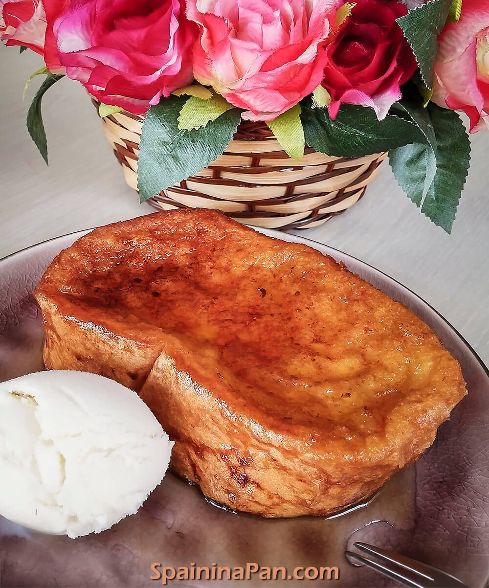 Spanish honey torrija served with a scoop of ice cream on a plate.