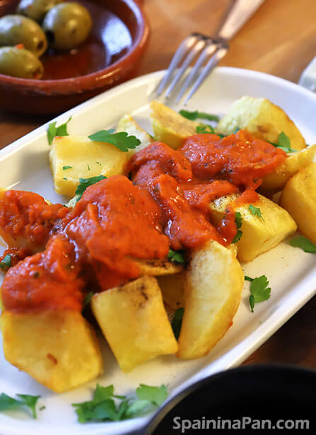 Patatas bravas with tomato based salsa brava in a tray.