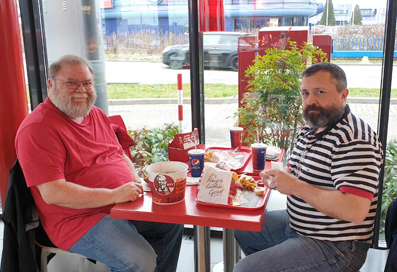 Two men having lunch at KFC on a window table.