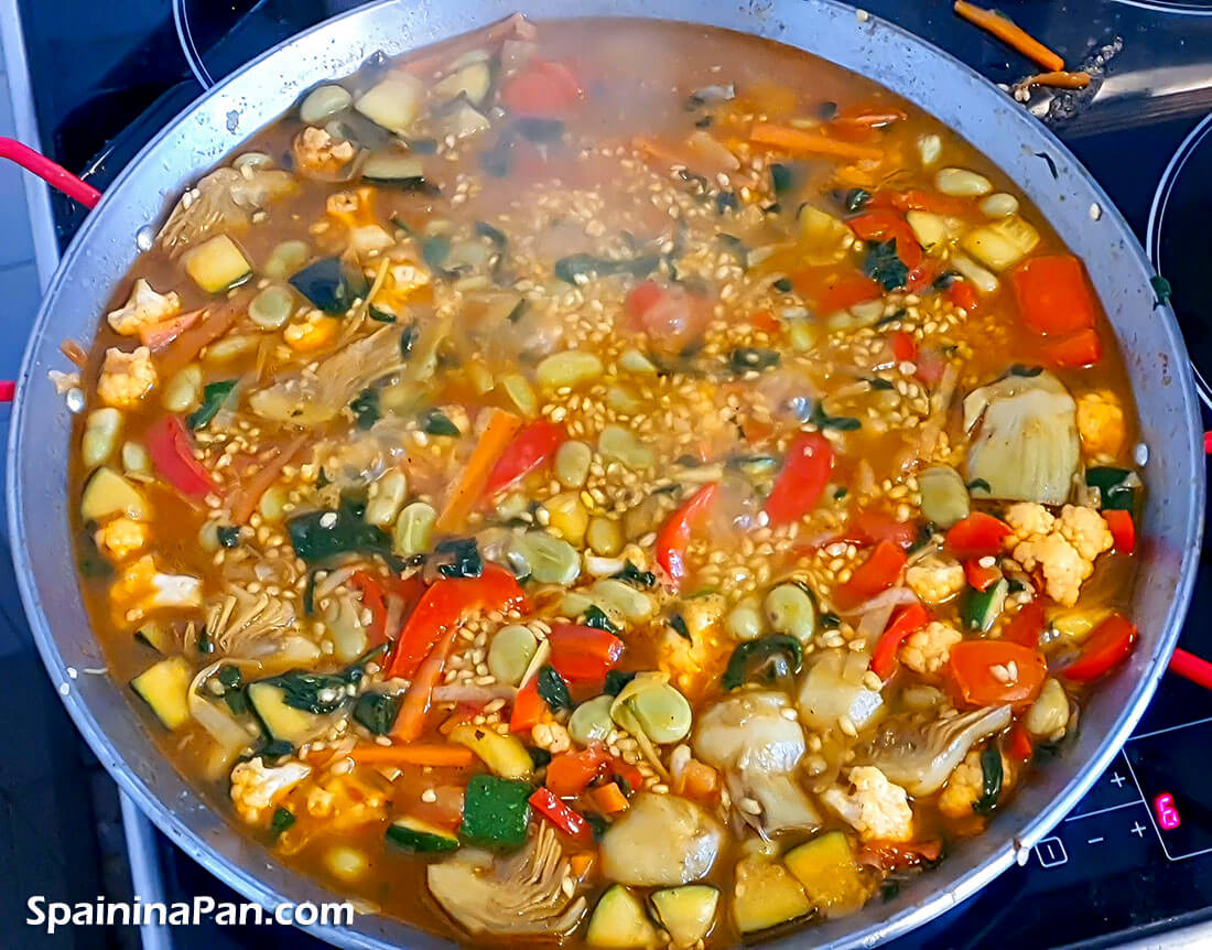 Vegetables paella simmering in a pan.